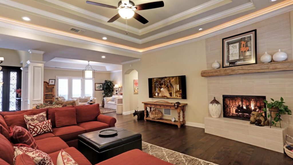 Dark wood flooring in a living room with a light stone fireplace.