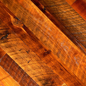Close-up of Rustic Heart Pine showcasing diagonal planks in diverse brown shades, highlighting its textured wood with visible grain and natural imperfections for a warm, earthy look.