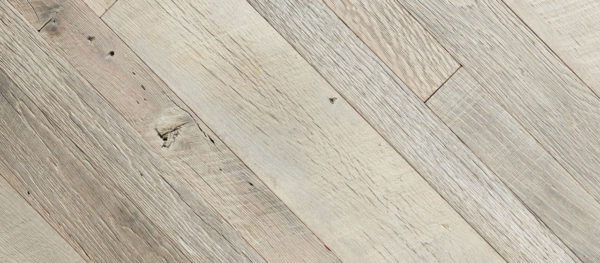 A close-up of the Old Grey Owl product showcases a light-colored wooden floor with a diagonal plank pattern. The natural grain, visible knots, and tonal variations evoke the serene beauty of nature's nuances, reminiscent of an owl's forest habitat.