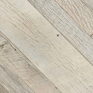 This close-up view showcases the Old Grey Owl flooring with its light-colored, distressed wood, rustic texture, and visible grain patterns. The diagonally laid planks highlight knots and subtle color variations reminiscent of weathered elegance.