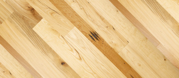 A close-up of Prairie Harvest wooden flooring features light and dark brown planks reminiscent of a prairie landscape. The varied wood grain, natural knots, and diagonal arrangement create a textured pattern that evokes the richness of harvest season.