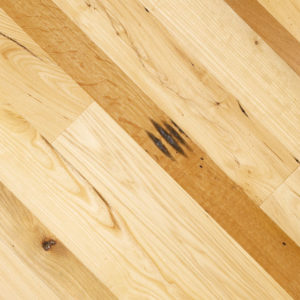Close-up of a wooden Prairie Harvest floor with light and medium brown planks. The hues showcase wood grain patterns and dark knots, creating texture and natural variation.