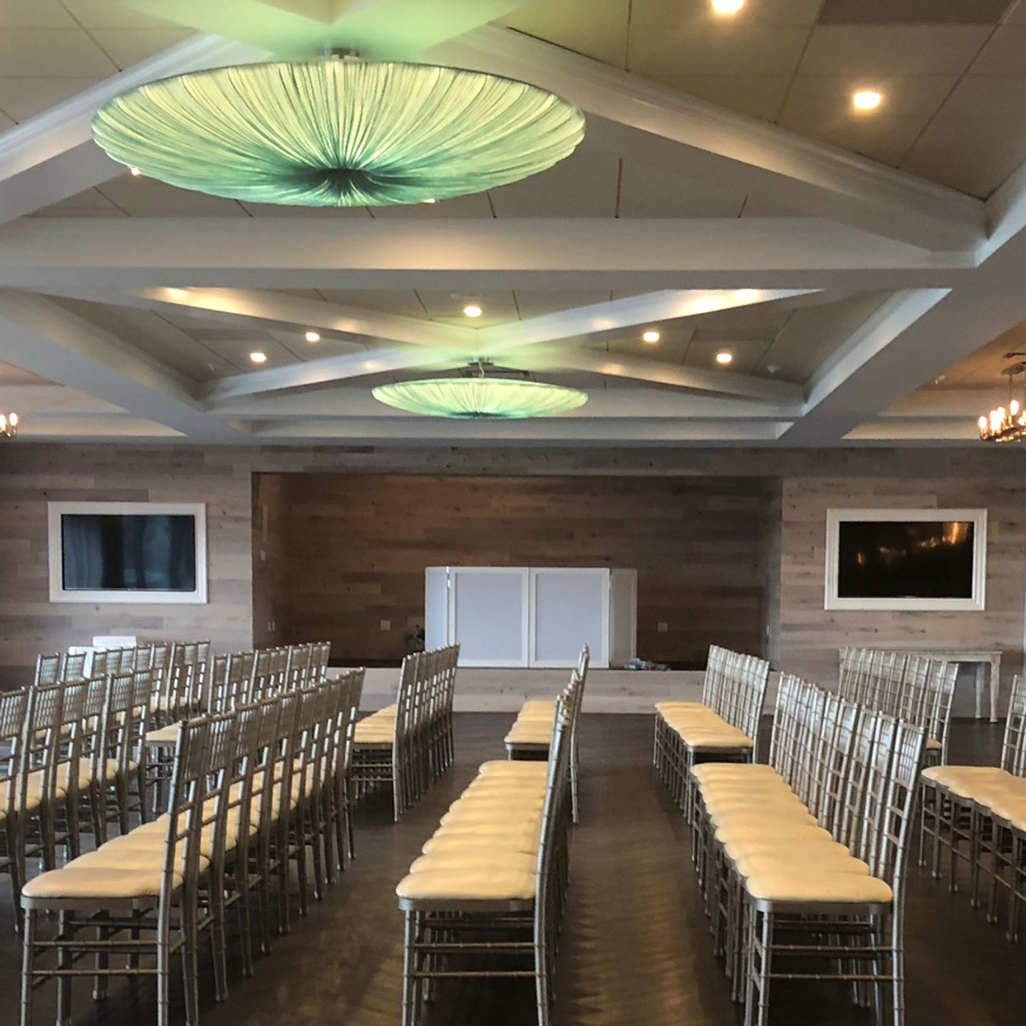 Rows of chairs in a room that features a whitewash wood panel wall.