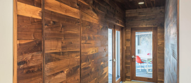 Well-lit hallway in an office building features wood-paneled walls.