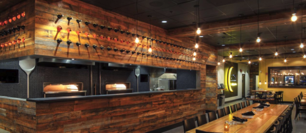 Restaurant bar area features dark wood wall panels that are showcased with strategic lighting.