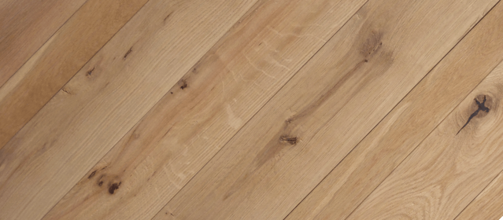 Close-up of Cascade Mountain light brown wooden floorboards with visible grain patterns and knots, evoking rustic Adirondack charm. The parallel arrangement highlights natural tone and texture variations.