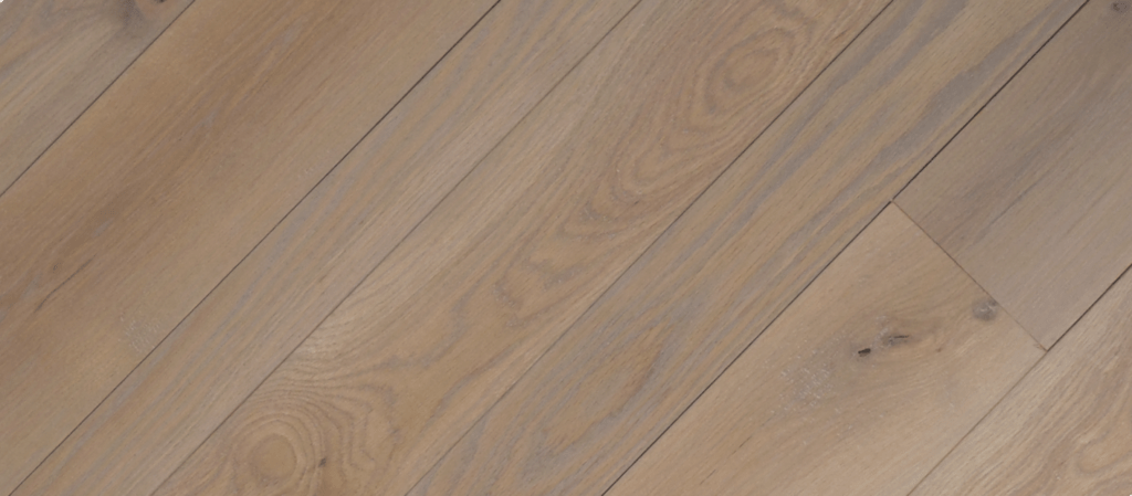 A close-up view of Valley Fog wooden floorboards in light brown with a smooth finish showcases the visible wood grain, featuring natural patterns and knots.