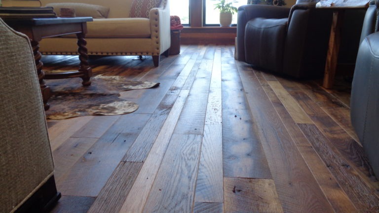 Close up of mixed width wood flooring installed in a living room.