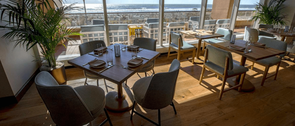 Wide plank wood flooring in a dining space with large windows