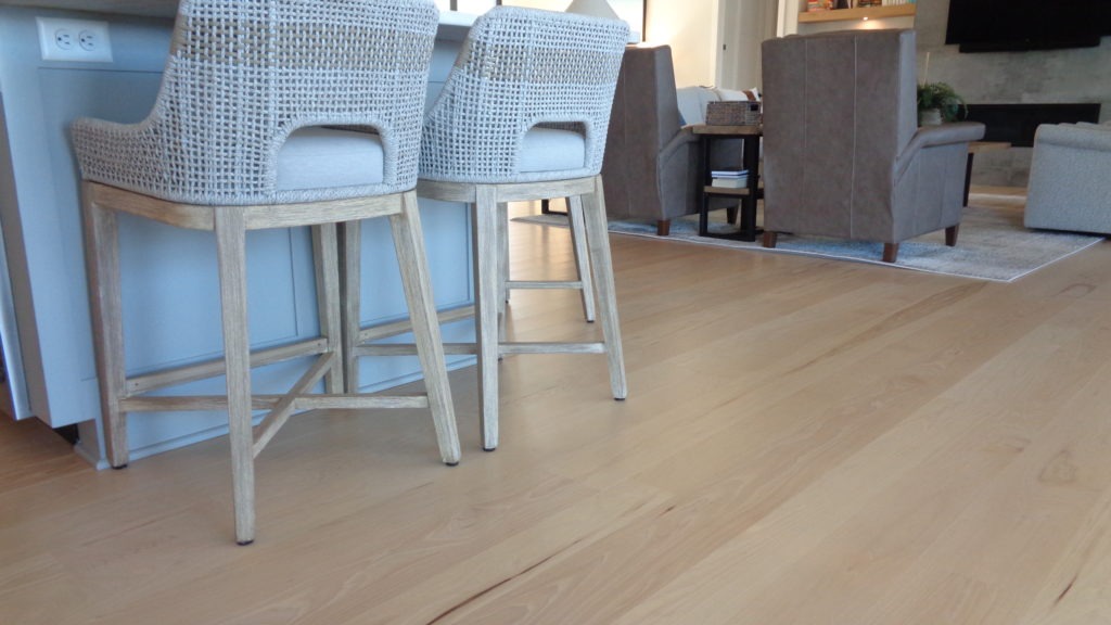 Close up of light wood flooring in open kitchen and living area.