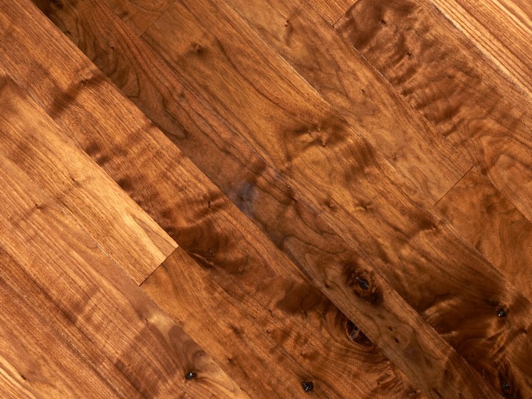 Close-up of a wooden floor with rich, warm tones. The surface features distinct grain patterns and natural blemishes, creating a textured appearance. Perfect for those seeking inventory specials that capture the natural beauty of wood with horizontally laid planks.