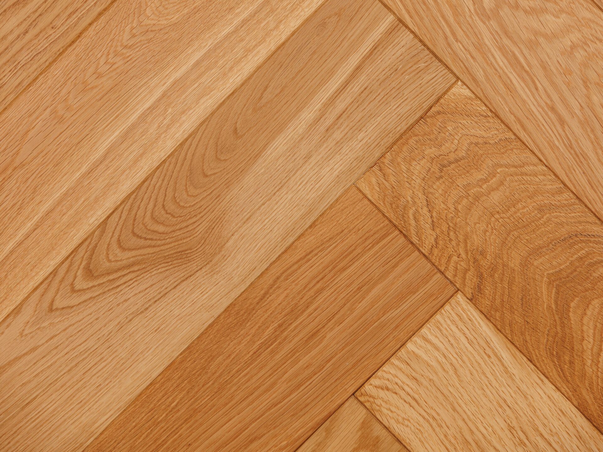 Close-up of milled hardwood for sale, arranged in a herringbone pattern, highlighting natural wood grain.